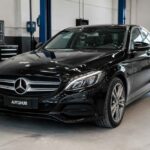 Czarny Mercedes-Benz Klasy C zaparkowany w jasnym warsztacie samochodowym