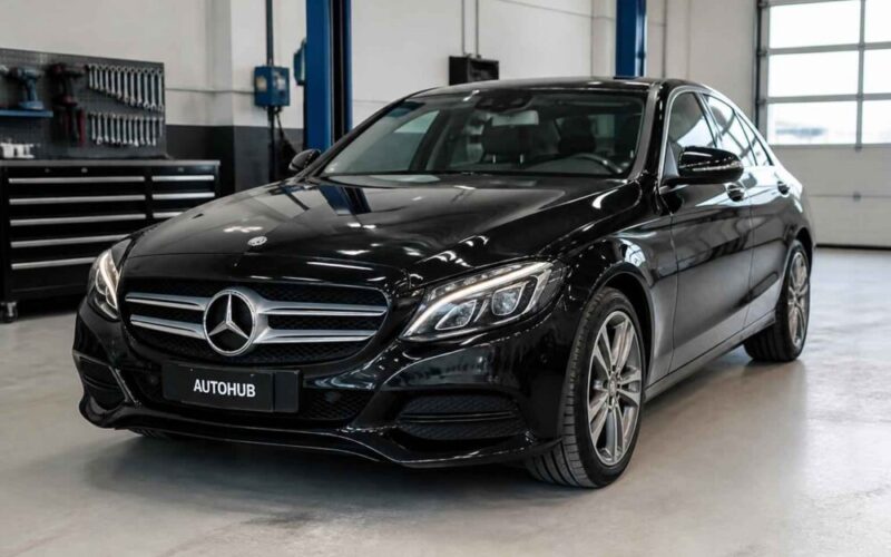 Czarny Mercedes-Benz Klasy C zaparkowany w jasnym warsztacie samochodowym