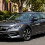 Szary Honda Accord zaparkowany przy krawężniku, w otoczeniu drzew i miejskiej zabudowy